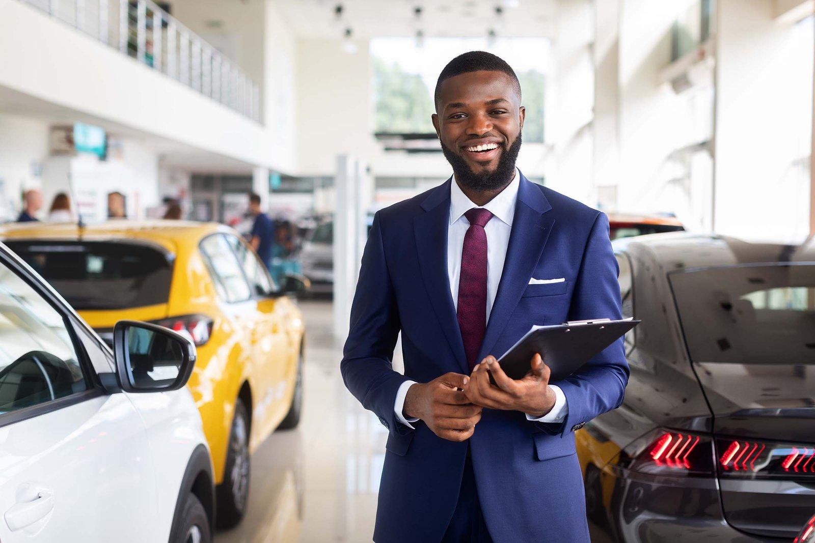 car-dealer-smiling-young-black-salesman-in-suit-at-2U486RL.jpg